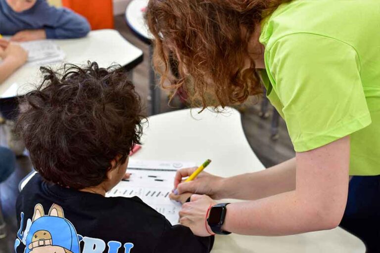 A child writing with a teacher's help